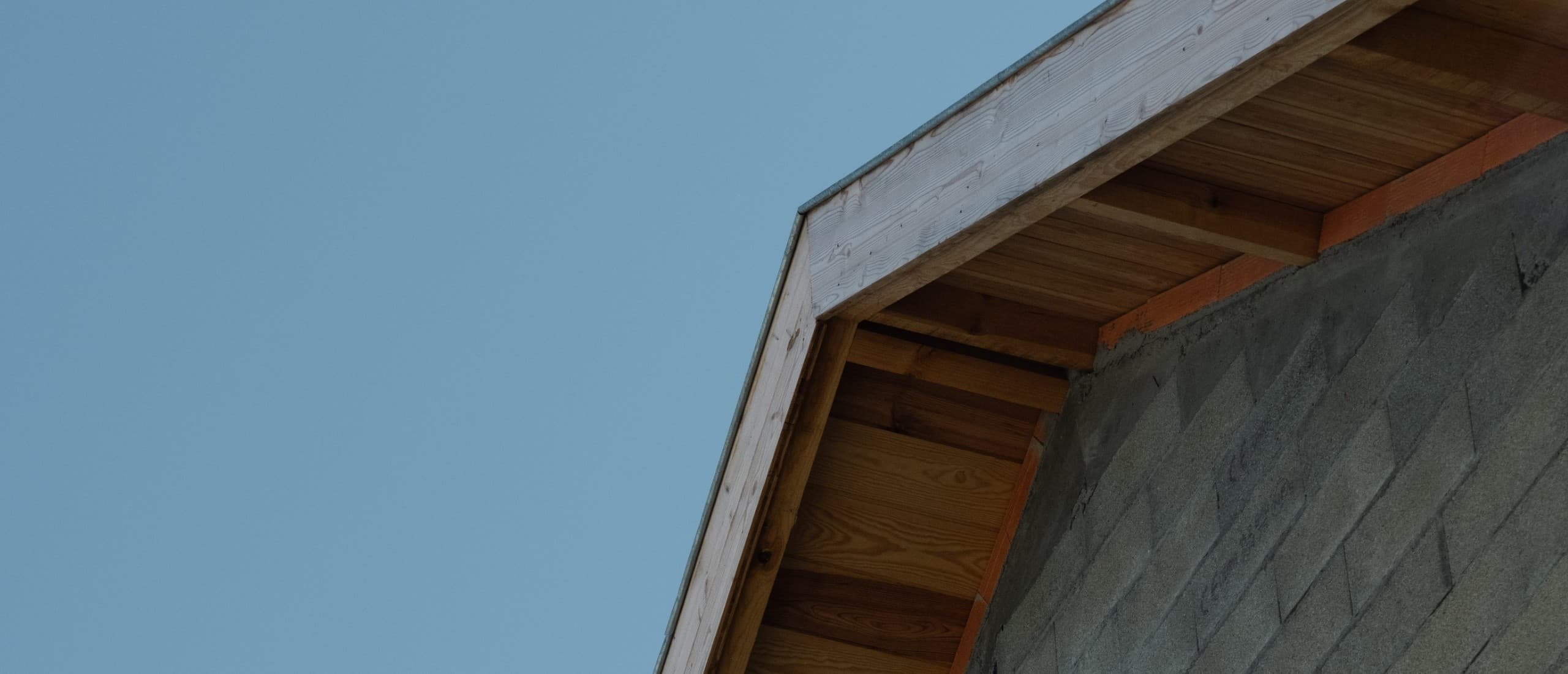 Les Ateliers Larrepunte — façade en bois et béton brut, vue d'angle sur la toiture sous le ciel basque.